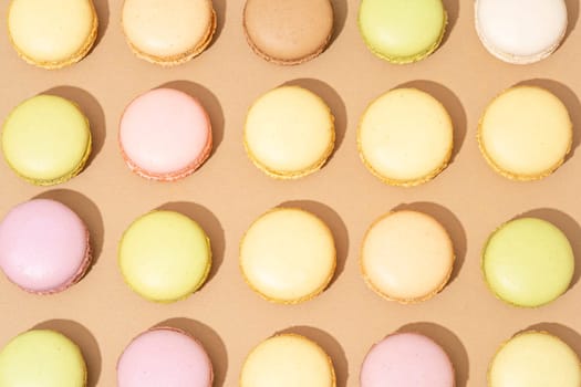 An assortment of macarons are neatly arranged in rows on a flat surface