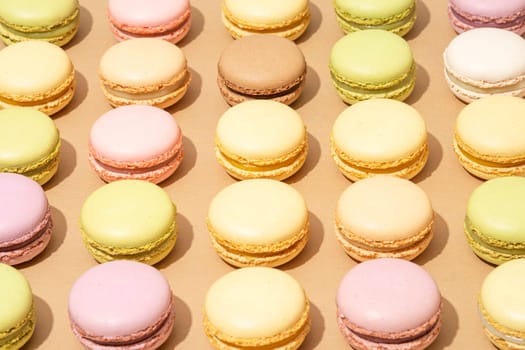 An assortment of macarons are neatly arranged in rows on a flat surface