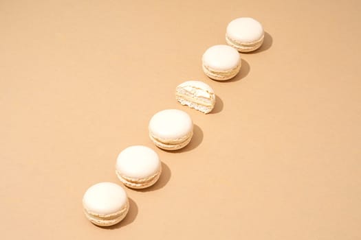 A still life image featuring six white macarons, arranged in a stack on top of each other