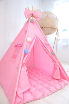 Playroom with Teepee. Modern room interior with play tent for child. pink children's wigwam in the room on the floor Scandinavian style with decor. High quality photo