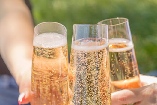 women drinking wine. three glasses white wine in female hands. flute glass of champagne with bubbles outdoors isolated against. garden scene blurred in the background. Cold Beer in glass. outdoor