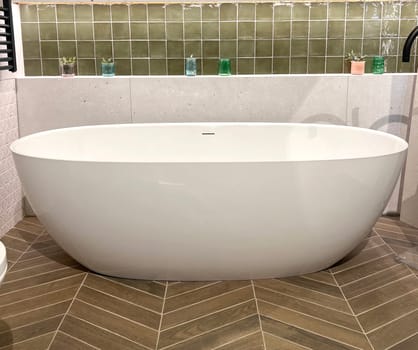 Modern ceramic bathtub . White tub in minimalistic bathroom interior. Porcelain bathtub with classic design in comfortable apartment or hotel room. home decor in spa center