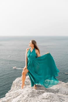 Woman sea trevel green dress. Side view a happy woman with long hair in a long mint dress posing on a beach with calm sea bokeh lights on sunny day. Girl on the nature on blue sky background