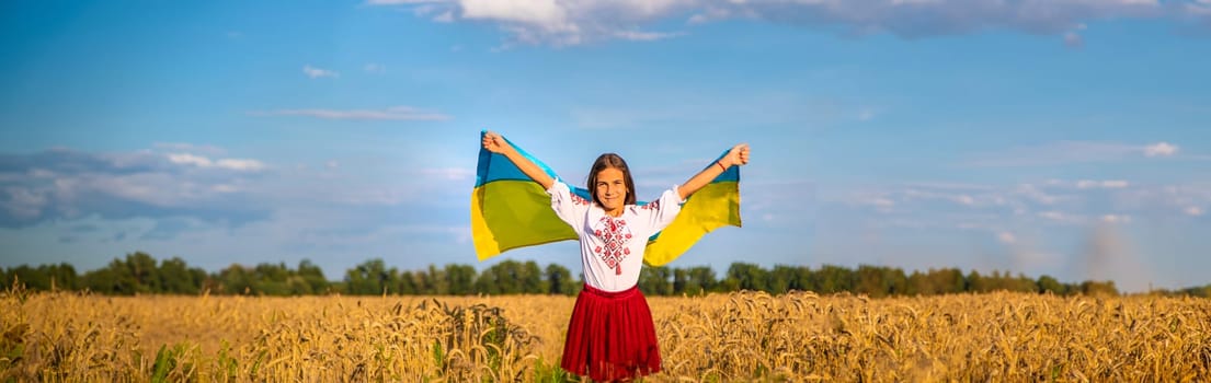 Child in a field of wheat with the flag of Ukraine. Selective focus. Kid.