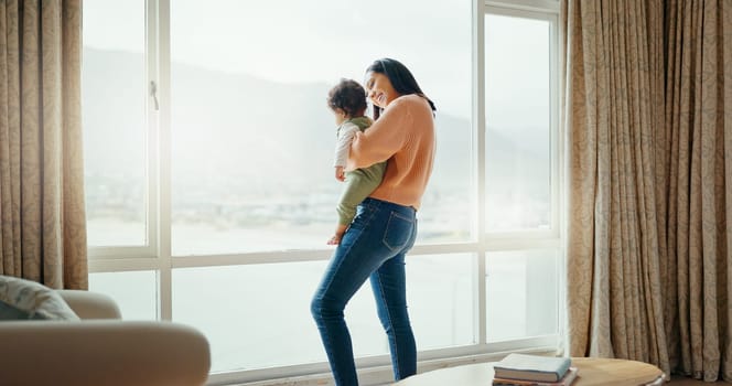 Care, happy and a mother with a baby in a house and looking at the view from a window. Smile, hug and a young mom holding a child for playing, bonding or love together in the morning as family.
