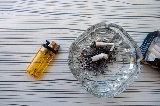 Cigarette, ashtray and lighter stand together on the table,