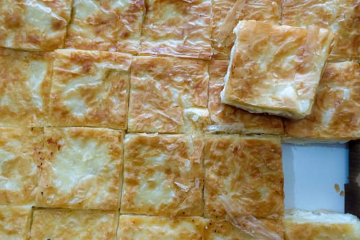 a tray full of pastries,turkish style cheese pie, water borek turkish style close-up, cheese pie,