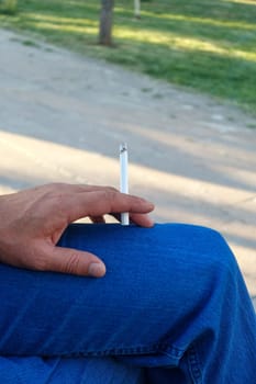 cigarette standing in a person's hand,close-up of a hand holding a cigarette,