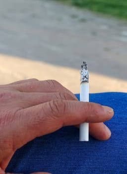 cigarette standing in a person's hand,close-up of a hand holding a cigarette,