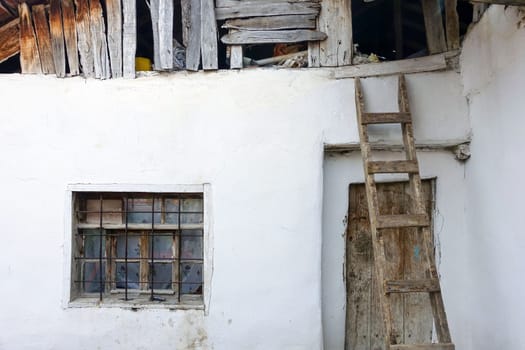 The old village house and the wooden ladder placed on its roof,