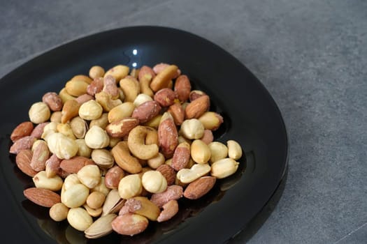 There is a plateful of nuts, hazelnuts, peanuts, cashews in the plate.