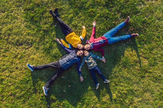 family top view. lying on the grass. sunny day. in green nature together. Aerial view Drone photography.