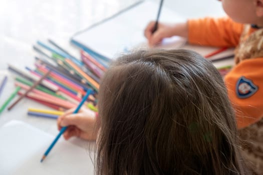 little girl coloring with crayons at the table,close-up of kindergarten kids coloring,