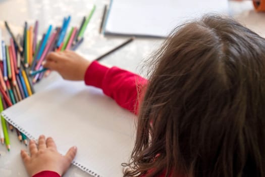 little girl coloring with crayons at the table,close-up of kindergarten kids coloring,