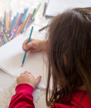 little girl coloring with crayons at the table,close-up of kindergarten kids coloring,