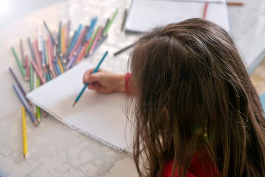 little girl coloring with crayons at the table,close-up of kindergarten kids coloring,