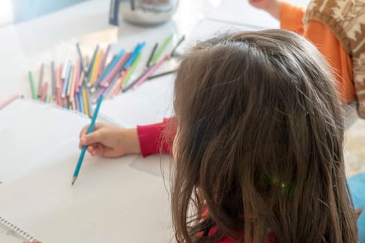 little girl coloring with crayons at the table,close-up of kindergarten kids coloring,