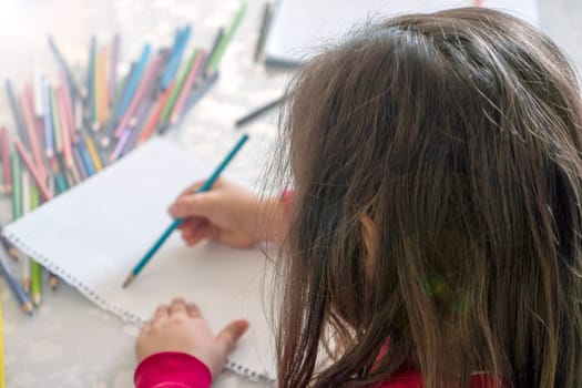 little girl coloring with crayons at the table,close-up of kindergarten kids coloring,