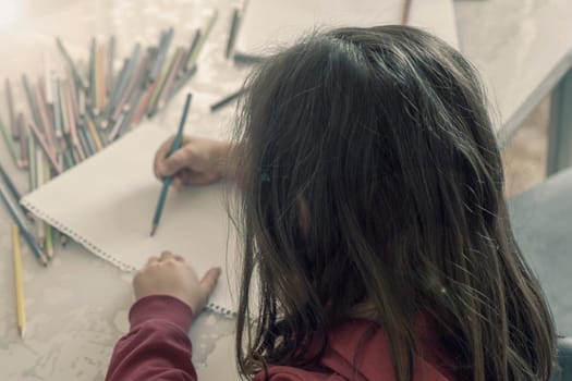 little girl coloring with crayons at the table,close-up of kindergarten kids coloring,