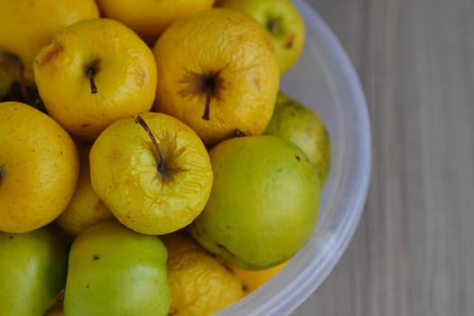 Rotting yellow apples, shriveled apples that have been sitting in a bowl for a long time,