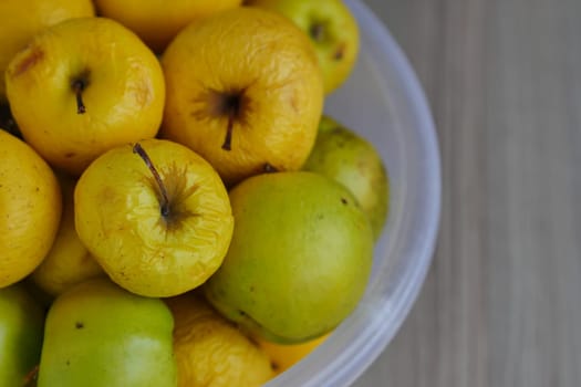 Rotting yellow apples, shriveled apples that have been sitting in a bowl for a long time,