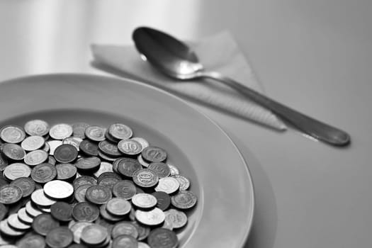 A plate full of coins on a table and a spoon next to it, eating money, concrete expression,