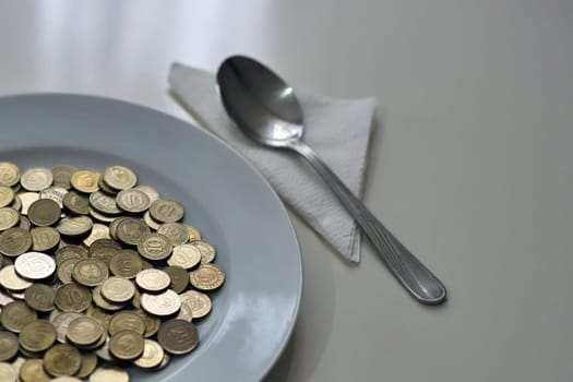 A plate full of coins on a table and a spoon next to it, eating money, concrete expression,