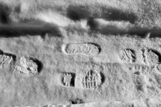 a person's shoe print on snow, a shoe print on black and white snow