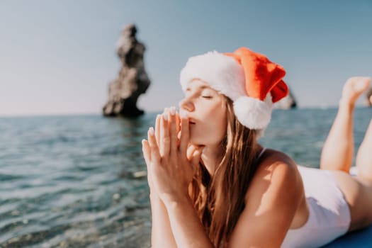 Close up shot of happy young caucasian woman looking at camera and smiling. Cute woman portrait in bikini posing on a volcanic rock high above the sea