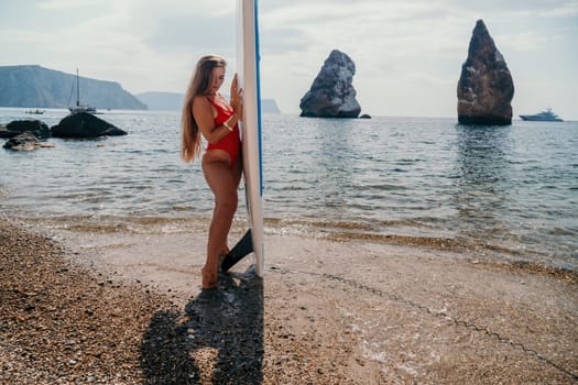 Close up shot of beautiful young caucasian woman with black hair and freckles looking at camera and smiling. Cute woman portrait in a pink bikini posing on a volcanic rock high above the sea