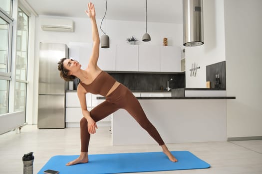 Beautiful young woman practicing yoga at home. Sport and wellbeing concept