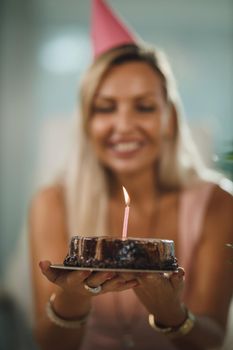 Alone attractive woman have birthday celebration at home during pandemic isolation and have video call with friends. She holding birthday cake with lighted candles.