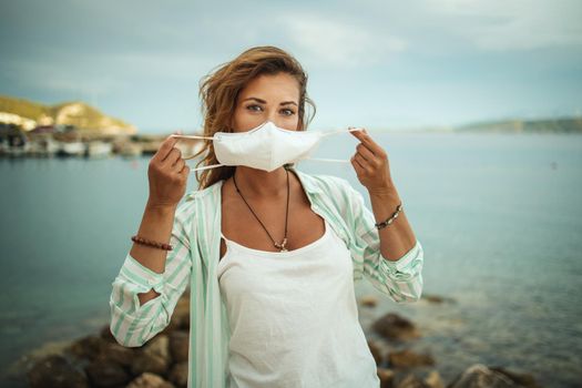 Shot of a happy young woman with protective N95 mask enjoying a vacation on the beach during the COVID-19.