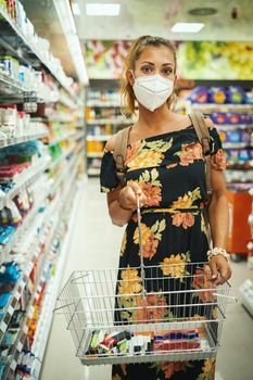 Shot of a young woman is wearing N95 protective mask while buying in supermarket during Covid-19 pandemic.