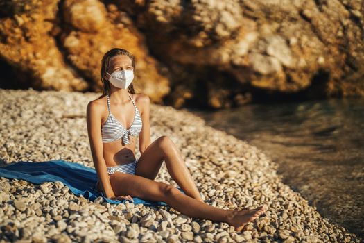 Shot of an happy teenager wearing surgical mask enjoying a vacation on the beach during the COVID-19.