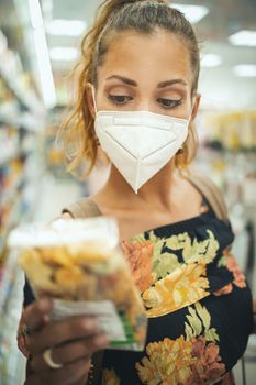 Shot of a young woman is wearing N95 protective mask while buying in supermarket during Covid-19 pandemic.