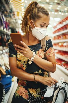 Shot of a young woman is wearing N95 protective mask while buying in supermarket during Covid-19 pandemic.