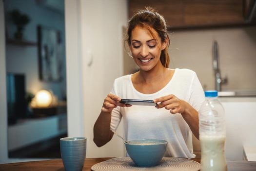 Beautiful young woman is filming her blog broadcast about healthy food at home.