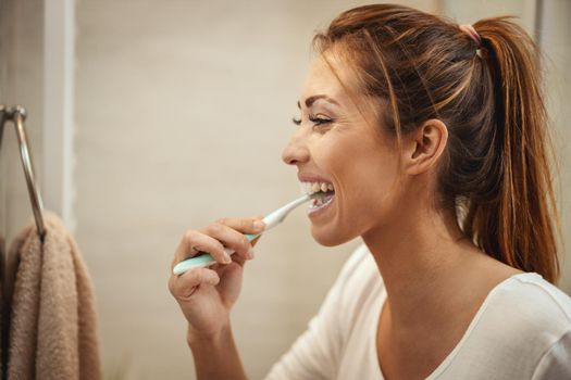 Shot of an attractive young woman who brush her teeth in the bathroom at home.