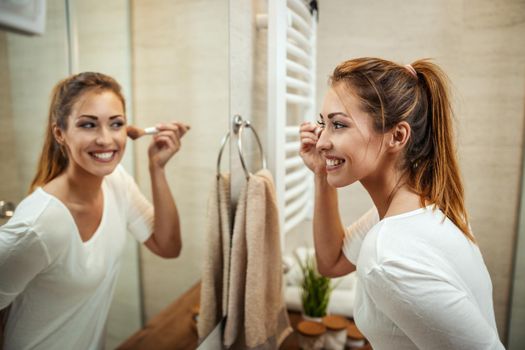Shot of an attractive young woman applying powder on mirror in the bathroom at home.