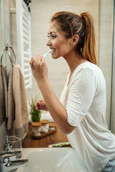 Shot of an attractive young woman who brush her teeth in the bathroom at home.