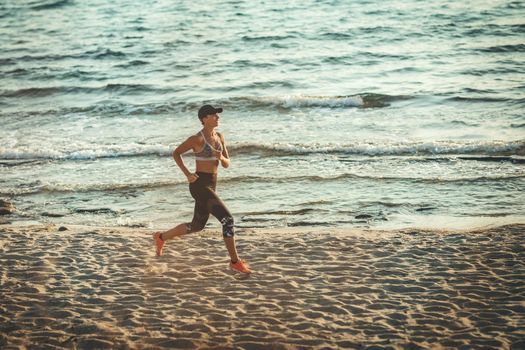 Young woman is running along the sea shore on the beach during the hot summer vacation day.