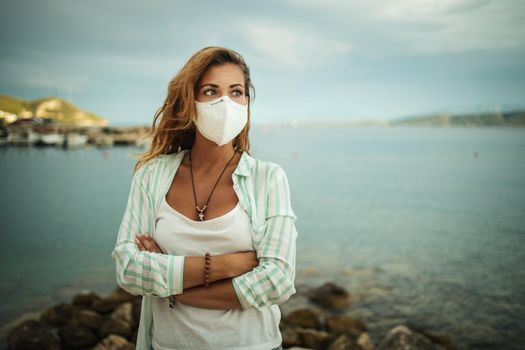 Shot of a young woman with protective N95 mask enjoying on the seaside during the COVID-19.