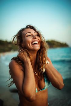 A beautiful young woman is having fun and relaxing on the beach at the sunset. 