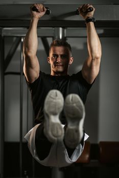 Muscular young man in sportswear focused on doing sit-up exercises during a strength training workout at the gym.