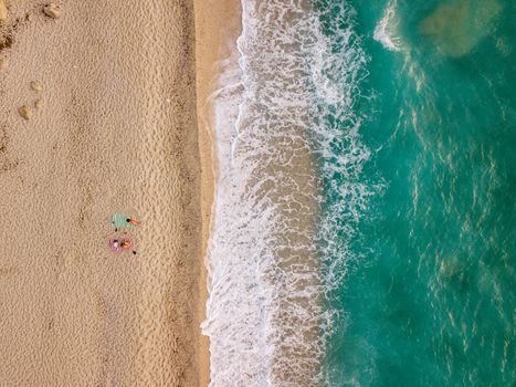 Aerial view of the amazing idyllic beach with two lonely people near waved clear Mediterranean sea at sunny day.