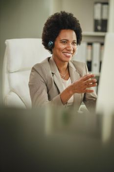 Shot of an attractive African businesswoman with headphones having video call while working on computer during COVID-19 pandemic.