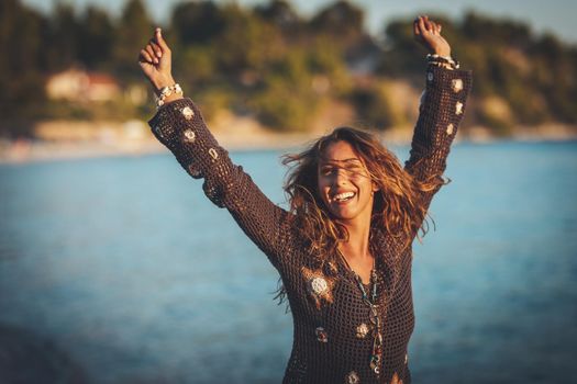 A beautiful young woman is having fun and relaxing on the beach at the sunset. 