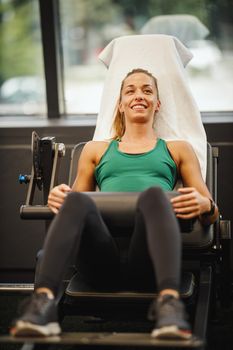 Shot of a muscular young woman in sportswear working out at the gym. She is doing glute bridge exercise for her gluteus on hip trust machine.
