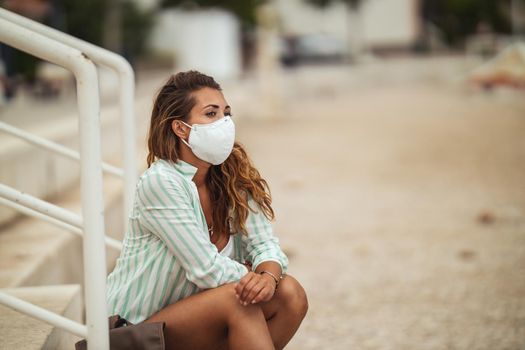 Shot of an attractive young woman with protective N95 mask enjoying on the beach during the COVID-19.